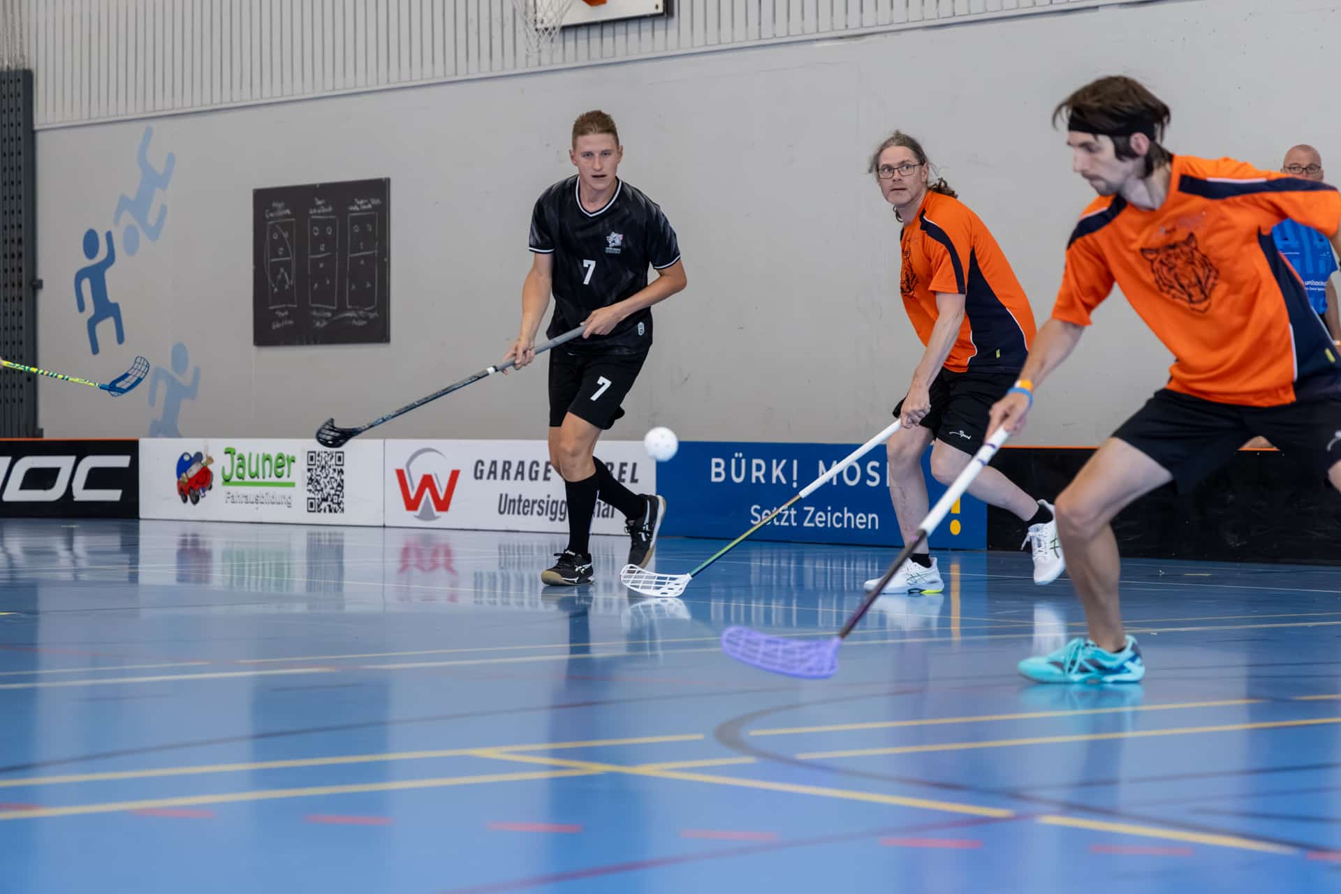 Giocatori di unihockey lottano per la pallina in una palestra
