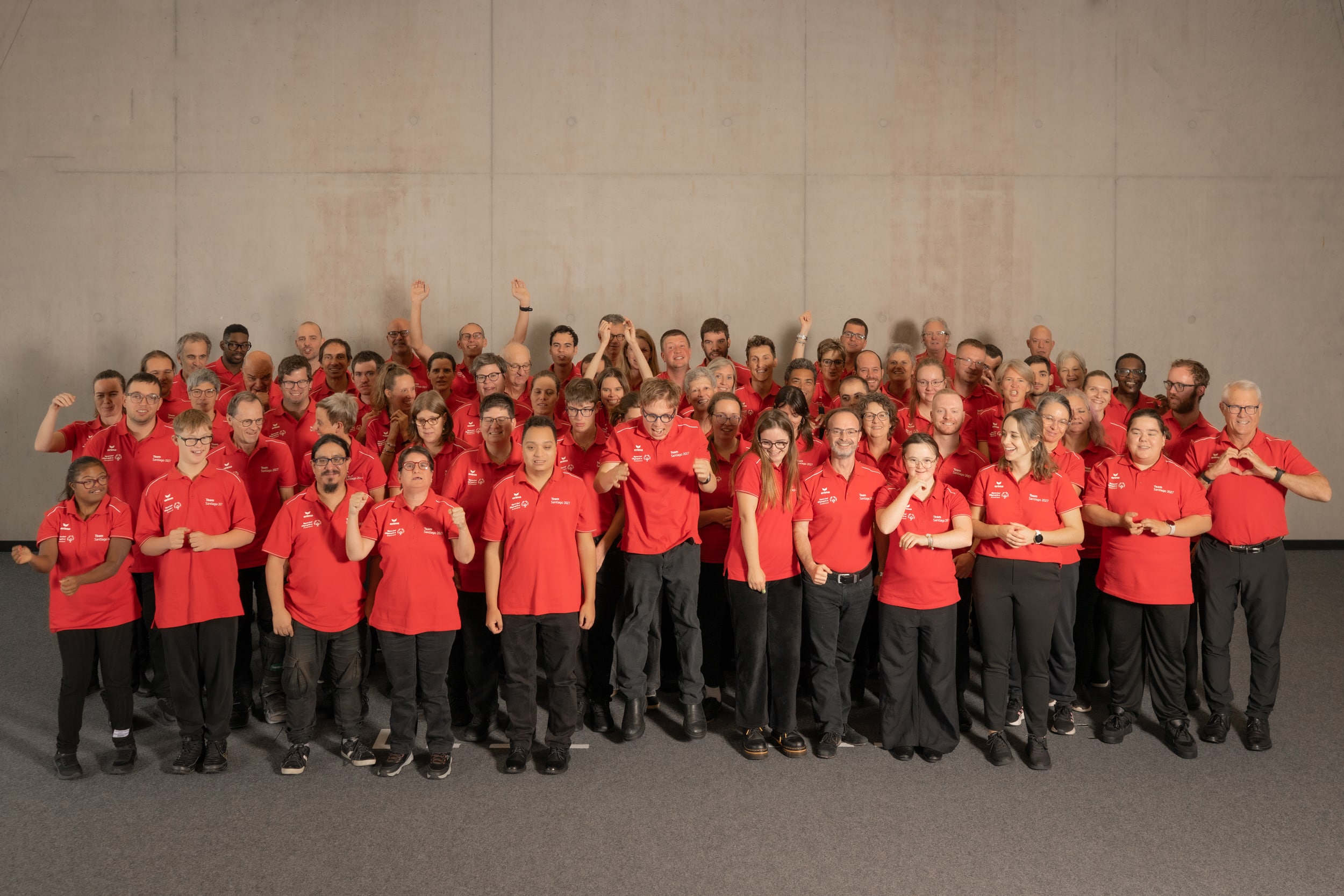 Großes Team in roten Poloshirts posiert begeistert